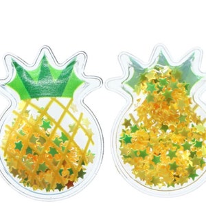 May include: Two clear plastic pineapple-shaped ornaments filled with gold and green glitter stars.