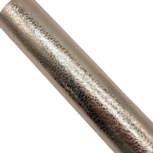 May include: A close-up of a metallic gold textured faux leather sheet. The sheet has a hammered or embossed look.