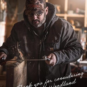 May include: A man wearing a camouflage cap and glasses, using a saw on a wooden plank. He is wearing a dark jacket. The image includes the text "Thank you for considering Ozarks Woodland" and the name "Adam Freeman".