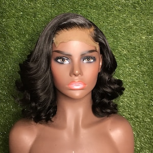 May include: A black human hair wig with a lace front and loose curls. The wig is styled in a bob and is on a mannequin head.