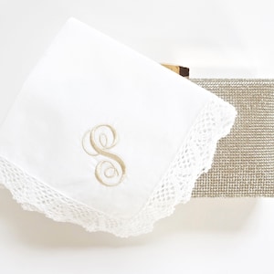 May include: A white handkerchief with a delicate lace trim and an embroidered letter "S" in the center.
