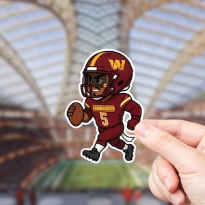 May include: A sticker featuring a cartoon illustration of a football player in a burgundy and gold uniform. The player is wearing a helmet with the letter "W" and the number "5" on the jersey. The word "Commanders" is also visible.