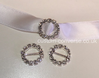 May include: Three silver-toned rhinestone buckle closures. Each buckle is a circle with a small bar across the center. The rhinestones are clear and sparkle.