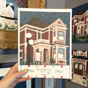 Puede incluir: Una impresi&oacute;n pintada a mano de una casa victoriana en tonos burdeos, crema y marr&oacute;n, sobre un cielo nocturno azul oscuro con estrellas. La impresi&oacute;n incluye una farola y el texto "Rosewood & Ivy Paper Co. EST 2019".