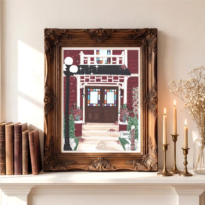 Puede incluir: Impresi&oacute;n enmarcada de una casa roja con techo negro y porche blanco, en un marco marr&oacute;n decorativo. Una farola negra est&aacute; a la izquierda. La impresi&oacute;n est&aacute; sobre una repisa blanca con velas y libros.