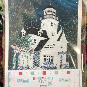 May include: Hand-painted art print of a white Victorian house with a tower, surrounded by lush greenery and flowers. The night sky is a deep blue with stars. The print is labeled "Rosewood & Ivy Paper Co."