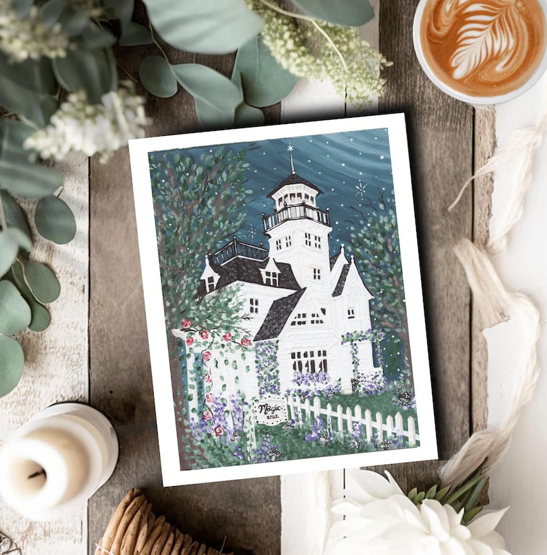 May include: A white and black illustration of a house with a tower, surrounded by greenery and a white picket fence. The artwork has a night sky background with stars. The word "Magic" is written on a small sign.