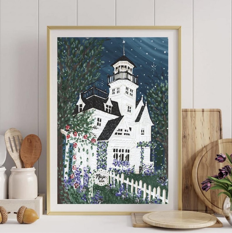 May include: A framed art print of a white house with a tower, surrounded by trees and a white picket fence. The artwork features a night sky with stars and the text "Magic wish". The print is in a gold frame.