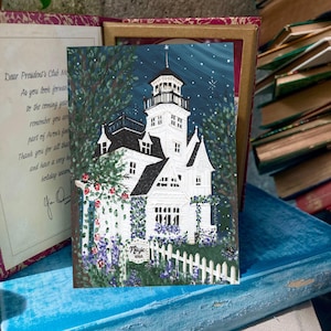 May include: A rectangular art print featuring a white Victorian-style house with a tall tower, dark roof, and a white picket fence. The scene includes green foliage, red and purple flowers, and a dark blue night sky with stars and the text Magic 2022.