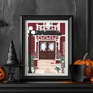 Puede incluir: Impresi&oacute;n en acuarela enmarcada de una casa roja con un porche blanco y vidrieras. La impresi&oacute;n est&aacute; decorada con flores y una farola. Un sombrero de bruja negro, una calabaza y una taza est&aacute;n en la repisa de la chimenea.