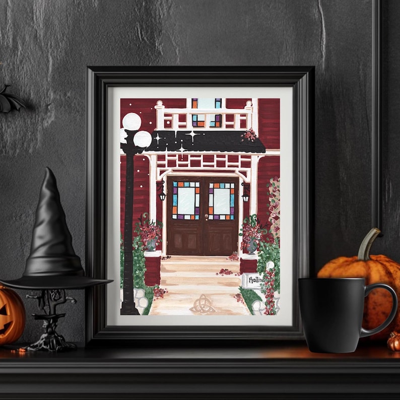 Puede incluir: Impresi&oacute;n en acuarela enmarcada de una casa roja con un porche blanco y vidrieras. La impresi&oacute;n est&aacute; decorada con flores y una farola. Un sombrero de bruja negro, una calabaza y una taza est&aacute;n en la repisa de la chimenea.