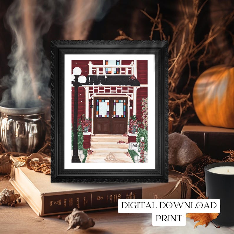 May include: A framed print of a red house with a black frame. The house has a dark brown door and colorful stained glass windows. The print is labeled "DIGITAL DOWNLOAD PRINT". The print is on a stack of books with a candle and a pumpkin in the background.
