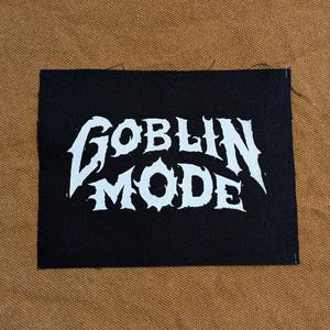 May include: Black fabric patch with white text that reads "GOBLIN MODE" in a stylized font.