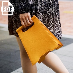 May include: A bright yellow leather handbag with a unique, angular design. The bag has a top handle and a flap closure.