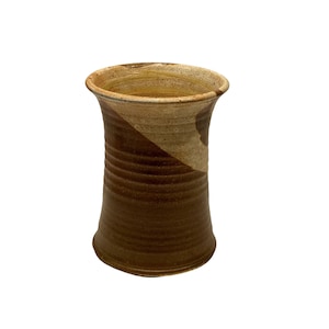 May include: A brown and tan ceramic vase with a textured finish. The vase has a wide mouth and a narrow base.