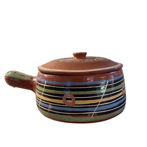May include: A terracotta pot with a lid, featuring a colorful geometric design in shades of green, blue, yellow, and black. The pot has a handle and is perfect for serving food.