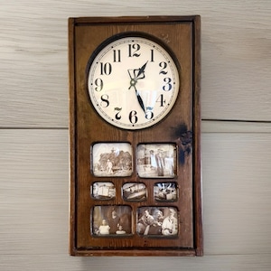 May include: A vintage wooden wall clock with a round clock face and a rectangular frame. The clock face has black numerals and hands. Below the clock face are six small photo frames containing black and white images.