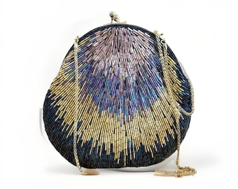 May include: A rounded clutch bag featuring an intricate pattern of glass beads in shades of navy blue, gold, and iridescent purple. The bag includes a gold-toned metal frame with a kiss-lock closure and a detachable gold-toned metal chain strap.