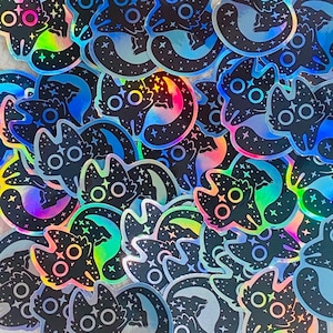 Puede incluir: Una colección de pegatinas holográficas iridiscentes con un diseño de gato negro con estrellas y una luna creciente. Las pegatinas son perfectas para agregar un toque de fantasía a las computadoras portátiles, botellas de agua, diarios y más.