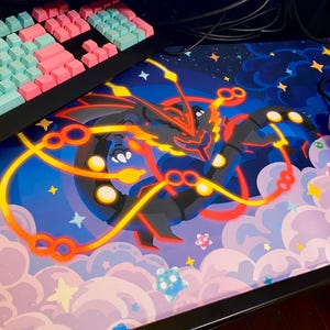 May include: A blue and pink gaming mouse pad with a black and red cartoon character in the center. The character is surrounded by yellow and orange glowing circles. The mouse pad has a starry night sky background with white clouds.