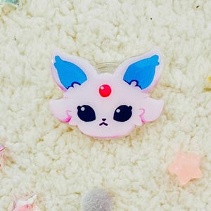 Puede incluir: Un personaje de dibujos animados rosa y azul con ojos grandes y una gema roja en la frente. El personaje est&aacute; hecho de pl&aacute;stico y tiene un acabado brillante.