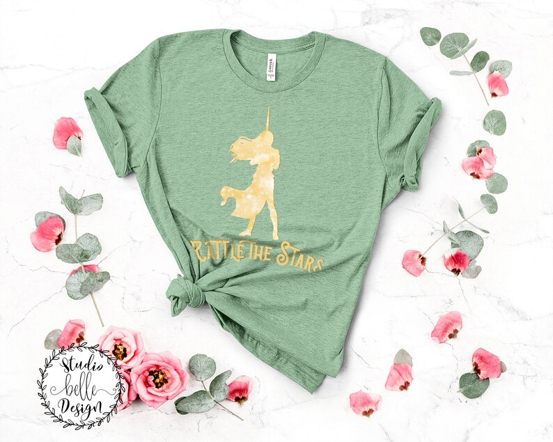 Puede incluir: Una camiseta verde con una silueta dorada de una mujer sosteniendo una espada y el texto "Battle the Stars".
