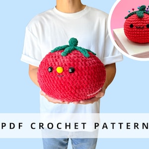 Puede incluir: Un gran tomate de ganchillo rojo y afelpado con un tallo y hojas verdes, y una cara sonriente con ojos negros y un punto amarillo. El texto "PDF CROCHET PATTERN" se muestra en un rectángulo blanco en la parte inferior de la imagen. Una tomate más pequeña se muestra en la esquina superior derecha.
