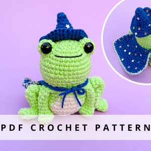 Puede incluir: Una rana de ganchillo verde, con un sombrero y capa de mago azules adornados con estrellas plateadas. La rana tiene una barriga blanca y ojos negros grandes. El texto "PDF CROCHET PATTERN" se muestra en una pancarta blanca.