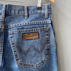 Pu&ograve; includere: Un paio di jeans blu denim con una toppa in pelle marrone Wrangler sulla tasca posteriore.