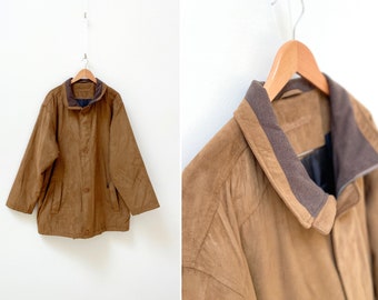 Könnte beinhalten: Eine braune Wildlederjacke mit einem braunen Cordkragen und einem Reißverschluss. Die Jacke hat zwei Taschen auf der Vorderseite und einen Knopfverschluss.