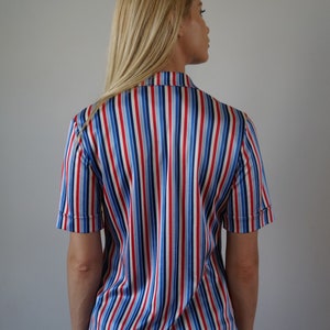 May include: A striped button-down shirt with red, blue, and white stripes. The shirt is made of a silky material and has short sleeves.