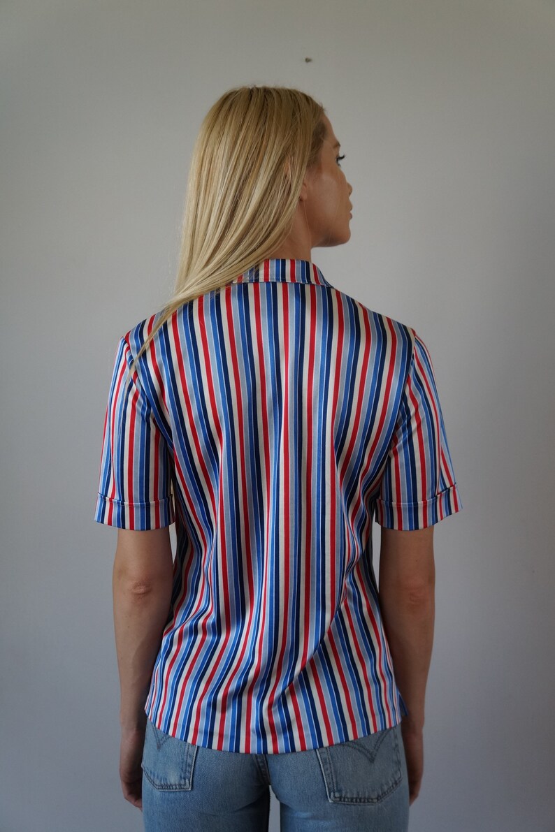 May include: A striped button-down shirt with red, blue, and white stripes. The shirt is made of a silky material and has short sleeves.