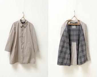 May include: A beige raincoat with a plaid lining. The raincoat has a button closure and two pockets. The lining is visible in the second image.