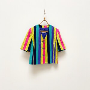 May include: A striped short-sleeved blazer with yellow, pink, purple, blue and black stripes. The blazer has a button closure and a v-neck.