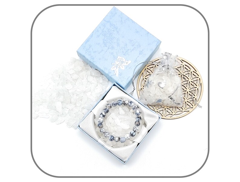 May include: A blue gift box with a white and gray crystal bracelet inside. The bracelet is made of round, gray and white stones. The box is surrounded by loose white crystals.