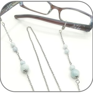 May include: A silver chain with light blue beads attached to a pair of glasses. The chain is designed to keep glasses from falling off.