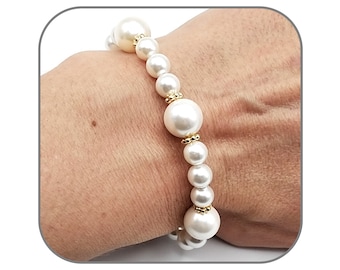 May include: A white pearl bracelet with gold accents. The bracelet is made of large, round pearls and small gold beads.