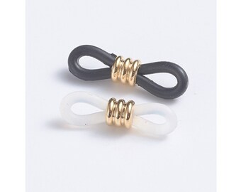 May include: Two pairs of eyeglass chain holders. One pair is black and the other is white. Both pairs have a gold metal connector.