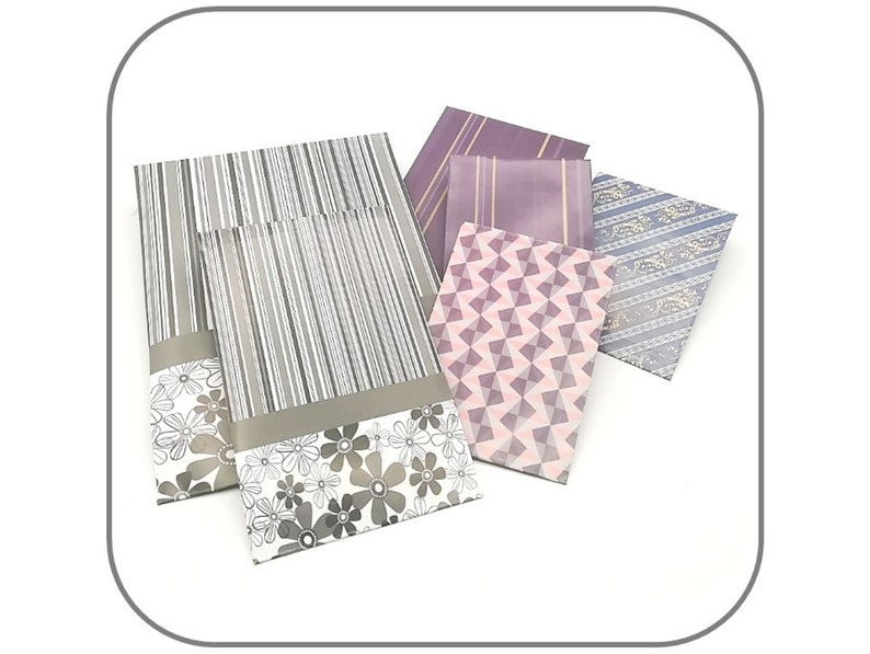 May include: Five decorative envelopes with different patterns. The envelopes are in shades of purple, pink, and gray. The patterns include stripes, geometric shapes, and floral designs.