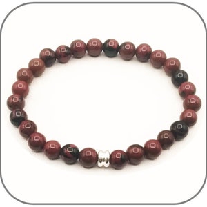 Peut inclure: Un bracelet élastique composé de perles rondes et polies dans des tons de bordeaux profond, de lie-de-vin et de noir. Les perles sont disposées en cercle et sont rehaussées par une perle intercalaire cylindrique en métal argenté.