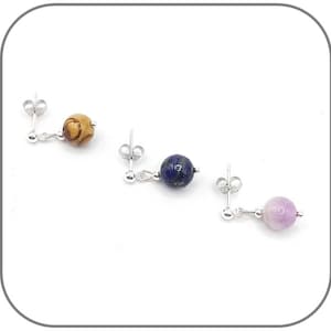 Op de afbeelding: Drie paar hangende oorbellen met zilveren oorbelsluitingen en haakjes. De oorbellen hebben ronde edelsteen kralen in bruin, blauw en paars.
