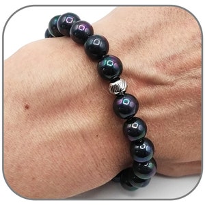 Puede incluir: Un brazalete de cuentas negras con un acento de cuentas plateadas. Las cuentas tienen un ligero brillo iridiscente.