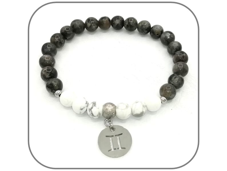 K&ouml;nnte beinhalten: Ein Armband aus schwarzen und wei&szlig;en Perlen mit einem silbernen Anh&auml;nger mit dem Zwillings-Sternzeichen. Das Armband hat eine silberne Zwischenperle und einen silbernen Verschluss.