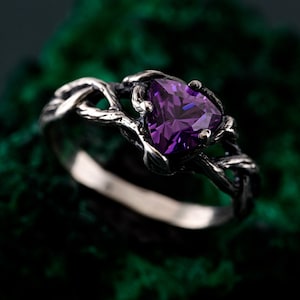 May include: A silver ring with a twisted branch design and a large, purple, triangular gemstone.