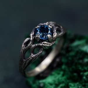 May include: A silver ring with a blue gemstone set in a branch-like design.
