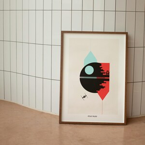 May include: A framed print of a minimalist geometric design inspired by Star Wars. The design features a black circle with a white circle inside, representing the Death Star, and a red and blue geometric shape.