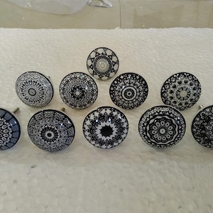 May include: Ten black and white ceramic cabinet knobs with intricate mandala designs.