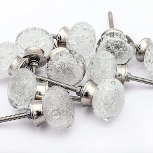 May include: A group of ten clear glass cabinet knobs with silver metal bases and screws. The knobs have a textured, bubbled surface.
