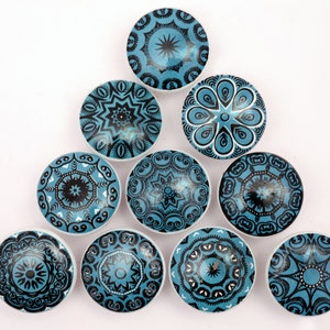 Puede incluir: Diez pomos redondos de cerámica con patrones geométricos azules y negros. Los pomos están dispuestos en forma de triángulo.