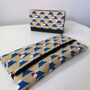 Op de afbeelding: Twee stoffen zakjes met een Japans berg- en zonontwerp. De zakjes zijn beige met blauwe bergen en rode zonnen. Het grotere zakje heeft een zwarte flap.
